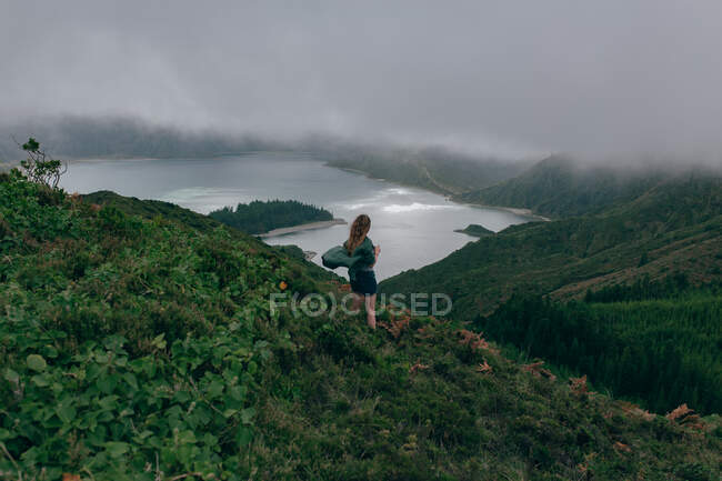 Жінка стоїть на високому пагорбі з озером нижче — стокове фото
