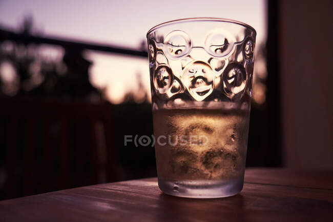 Verre transparent avec motif créatif et rempli de boisson debout sur une table en bois marron — Photo de stock