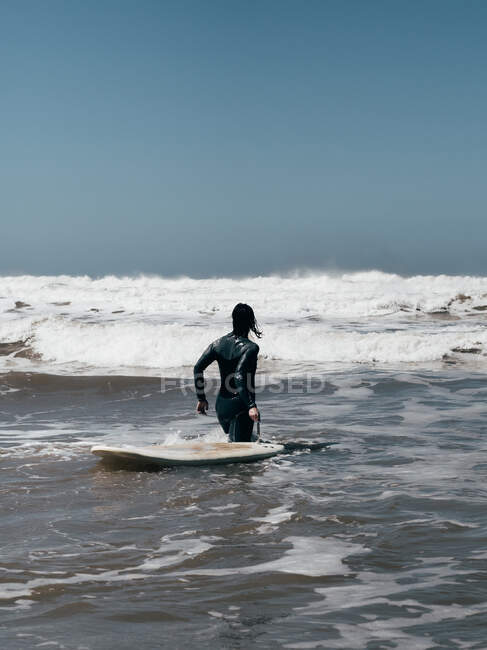 Человек с доской для серфинга идет к океану — стоковое фото