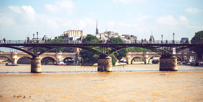 Puente que cae sobre el río Sena marrón en París en el fondo del paisaje urbano - foto de stock