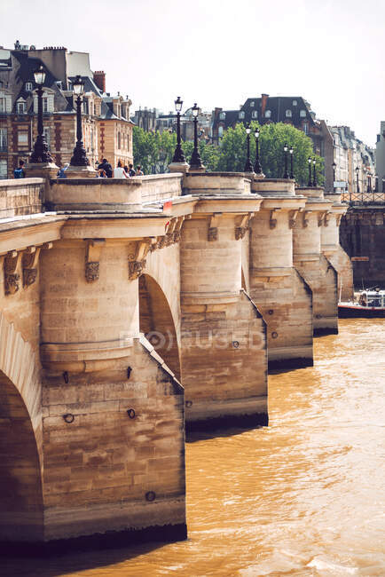 Stone Bridge falling over brown river Seine in Paris on background of cityscape — Stock Photo