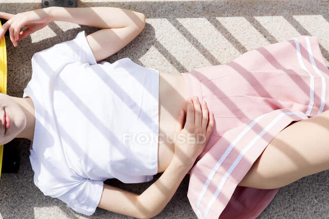 Дівчина-підліток в спідниці лежить на асфальті — стокове фото