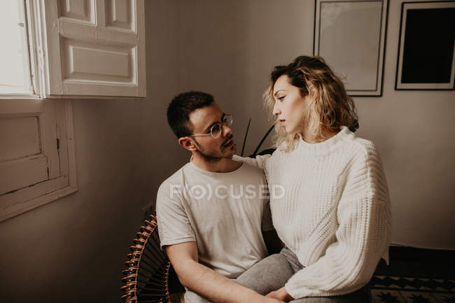 Щаслива пара сидить у кріслі і дивиться один на одного під час зв'язку вдома — стокове фото