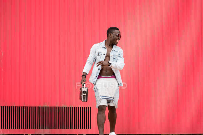 Африканский американец, стоящий с винтажным радиоприбором на красном фоне — стоковое фото