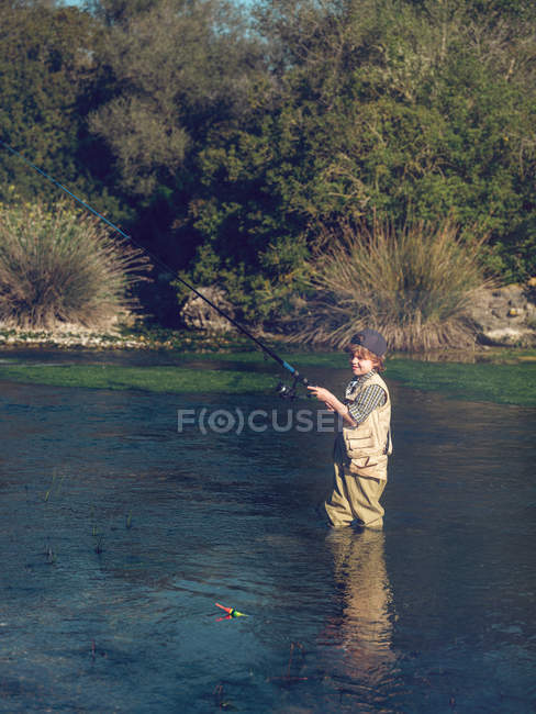 Niño pescando en el río - foto de stock
