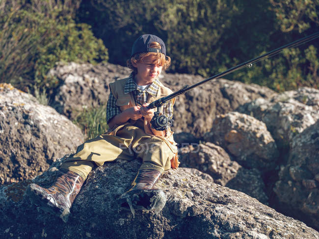 Giovane ragazzo seduto e pesca — Foto stock