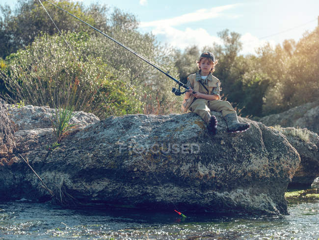 Jeune garçon assis et pêche — Photo de stock