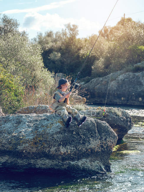 Giovane ragazzo seduto e pesca — Foto stock