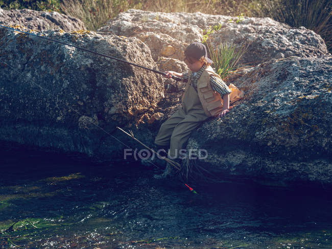 Jeune garçon assis et pêche — Photo de stock