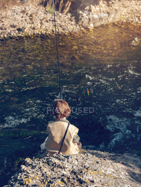 Хлопчик сидить і рибалить — стокове фото