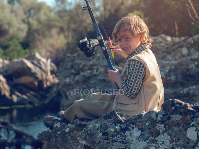 Young boy sitting and fishing — Stock Photo