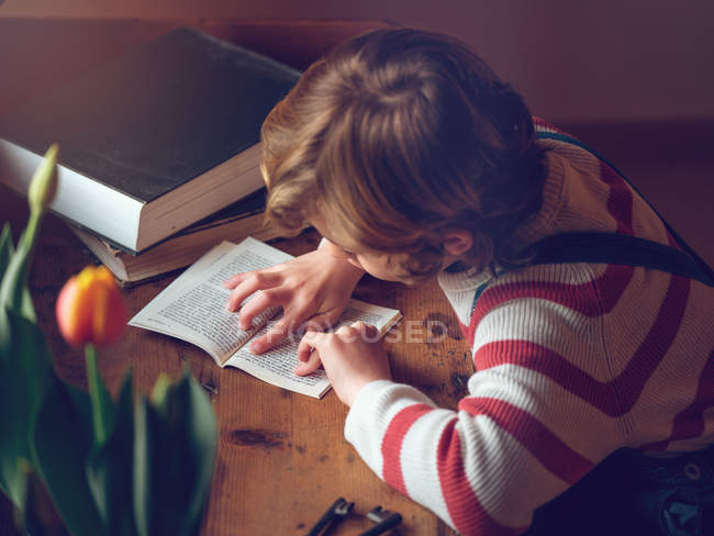 Boy reading book at table — Stock Photo