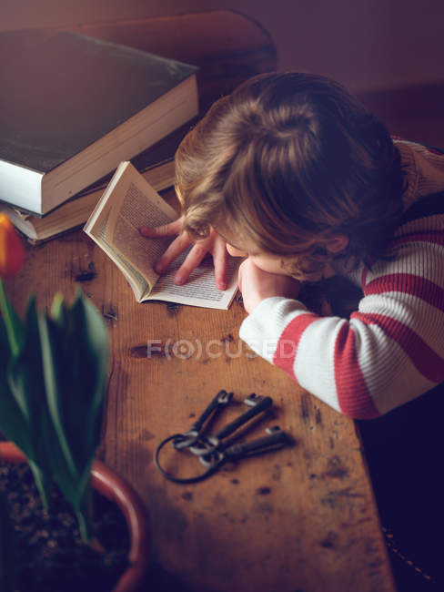 Boy reading book at table — Stock Photo