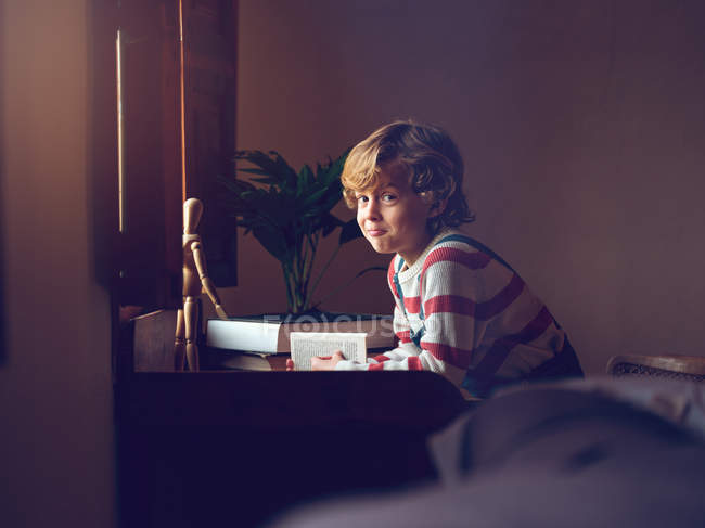 Junge liest Buch am Tisch — Stockfoto
