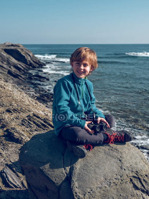 Fröhlicher Junge mit Fernglas am Meer — Stockfoto