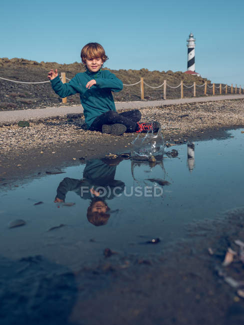 Junge am Leuchtfeuer reflektiert in Pfütze — Stockfoto