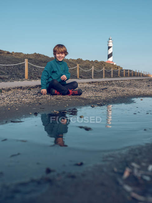 Мальчик на маяке отражается в луже — стоковое фото