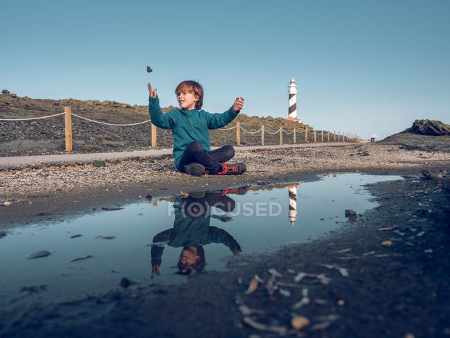 Мальчик на маяке отражается в луже — стоковое фото