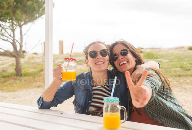 Las mujeres sonrientes se divierten con frascos con jugo - foto de stock