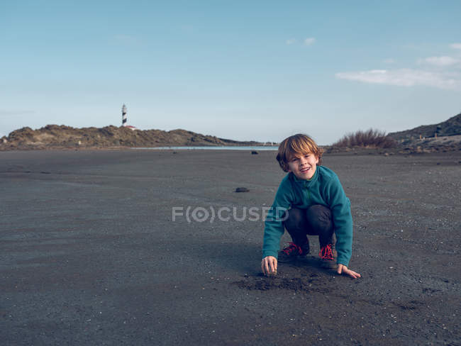 Garçon joyeux jouant avec le sable — Photo de stock
