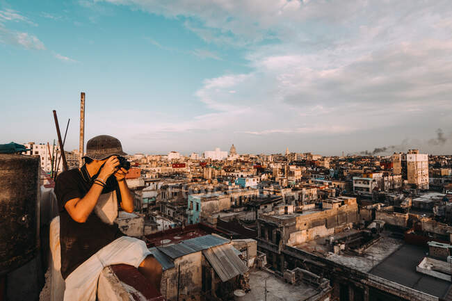 LA HABANA, CUBA - 1 MAGGIO 2018: Uomo che usa la macchina fotografica e fotografa il vecchio quartiere povero della città cubana alla luce del sole. — Foto stock