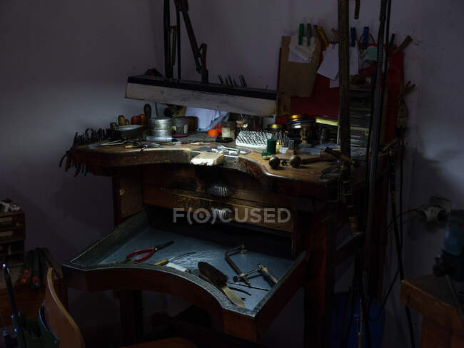 Mesa con diferentes instrumentos y luz en fábrica de joyería antigua. - foto de stock