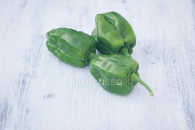 Fresh green peppers on white wooden table — Stock Photo