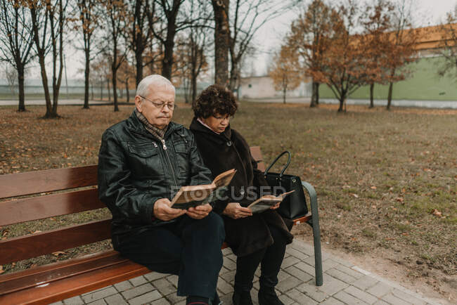 Старша пара читає книжки в парку. — стокове фото