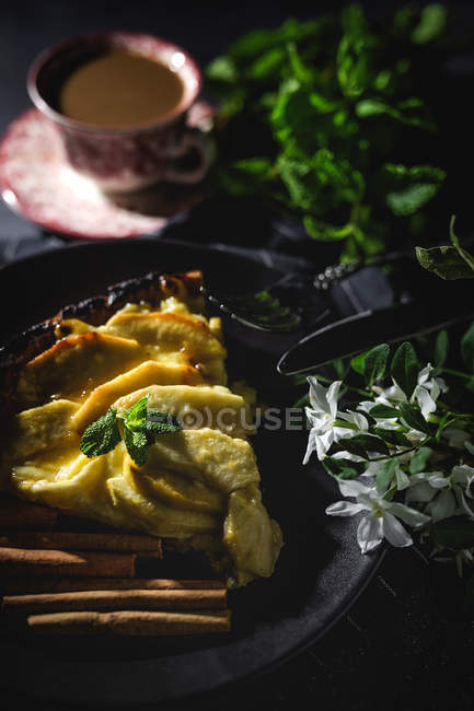 Apple pie with cinnamon and mint served on black plate — Stock Photo