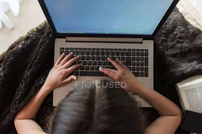 Невпізнавана дівчина використовує ноутбук на ковдрі — стокове фото