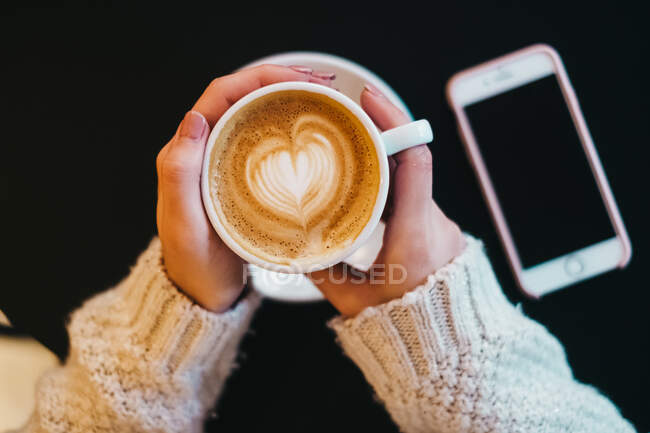 Woman with cup of drink near smartphone — Stock Photo