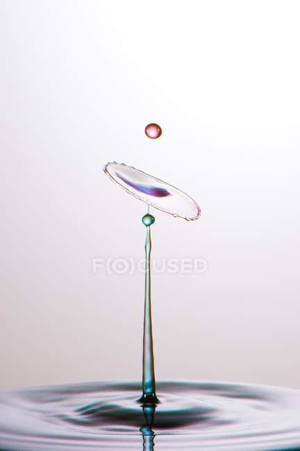 Primer plano de salpicadura de líquido transparente de color sobre fondo gris - foto de stock