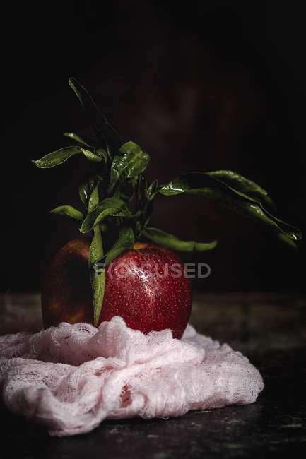 Raw red apple with leaves on dark table — Stock Photo