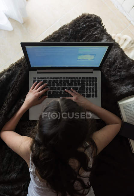 Неузнаваемая девушка с ноутбуком на одеяле — стоковое фото
