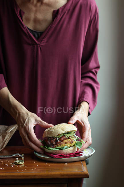 Mujer de las cosechas disfrutando de cerveza y hamburguesa vegetariana - foto de stock
