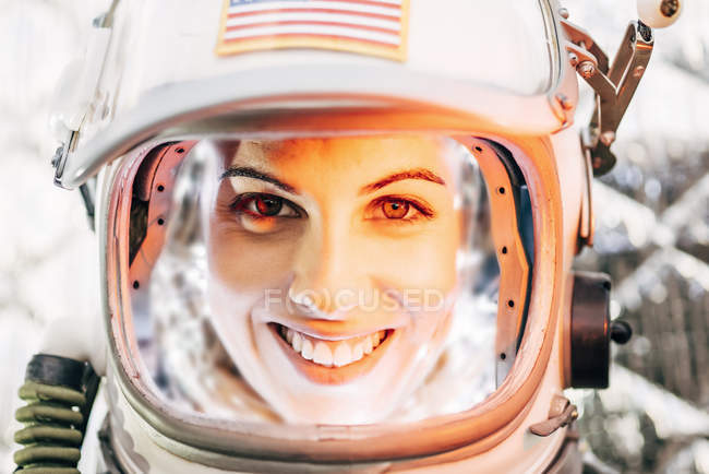 Menina sorrindo vestindo capacete antigo espaço e traje espacial no fundo da folha — Fotografia de Stock