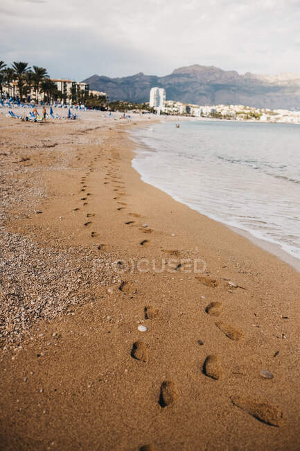 Tracce di piedi umani sulla sabbia bagnata vicino al mare che ondeggia ad Altea, Spagna — Foto stock