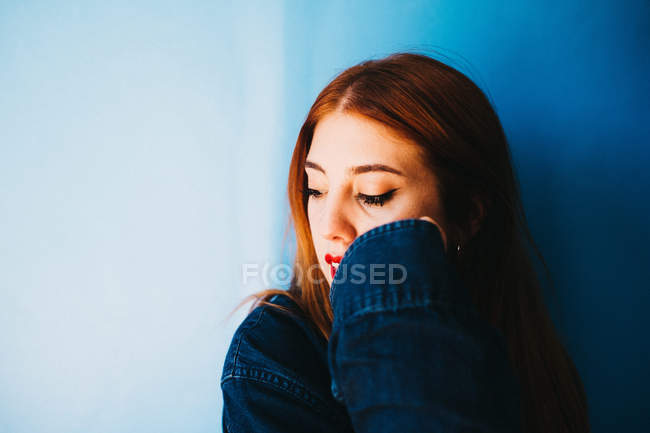 Belle femme debout près du mur bleu — Photo de stock