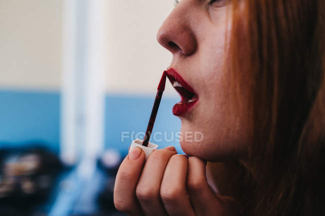 Attraktive rothaarige Frau rouging Lippen — Stockfoto