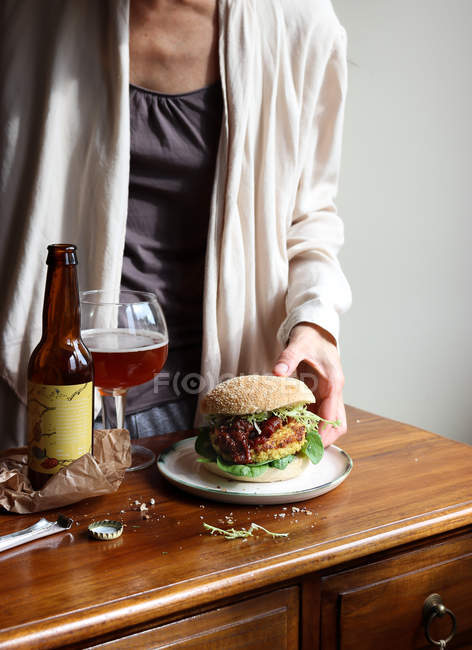 Primer plano de la mujer disfrutando de cerveza y hamburguesa vegetariana - foto de stock