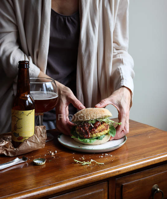 Close-up de mulher desfrutando de cerveja e hambúrguer vegetariano — Fotografia de Stock