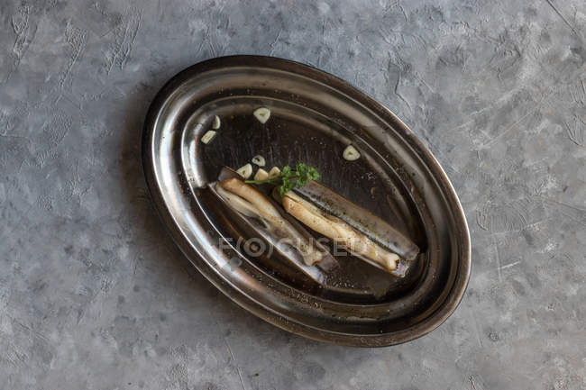 Тарелка из сырых бритвенных моллюсков на льду на серой поверхности — стоковое фото