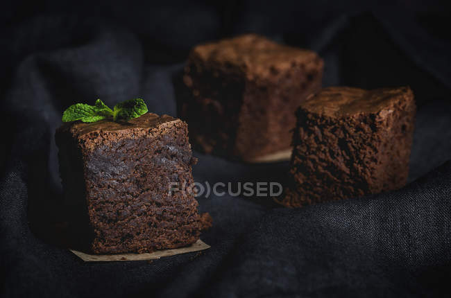 Stücke Schokolade Brownie mit Minze auf schwarzem Stoff — Stockfoto