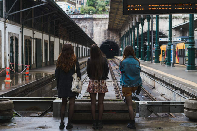 Vista traseira senhoras a olhar para os caminhos-de-ferro a correr num túnel num depósito no Porto, Portugal — Fotografia de Stock