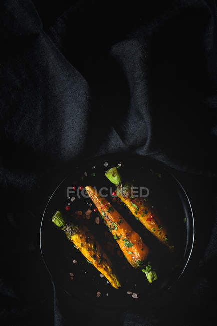 Cenouras assadas saudáveis com ervas e especiarias em tecido preto — Fotografia de Stock