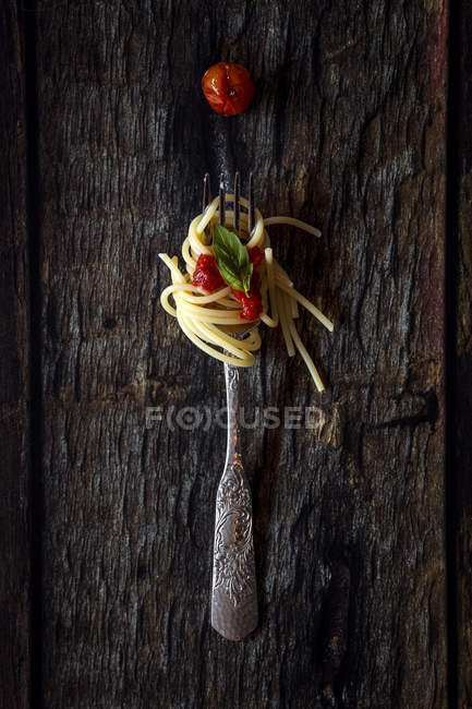 Espaguete com molho de tomate em garfo no fundo de madeira escura — Fotografia de Stock