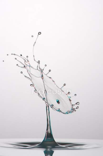 Close-up de respingo de líquido transparente de cor no fundo cinza — Fotografia de Stock