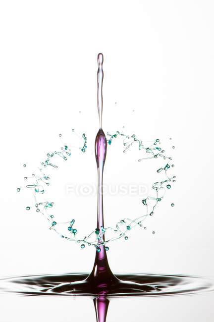 Splash of transparent liquid of color on white background — Stock Photo
