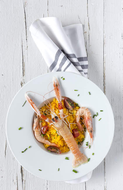 Hausgemachte Paella mit Krebsen und Garnelen auf Teller auf weißem Holztisch — Stockfoto