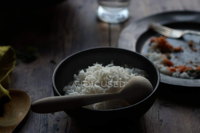 Schüssel Reis und leerer Teller auf rustikalem Holztisch — Stockfoto